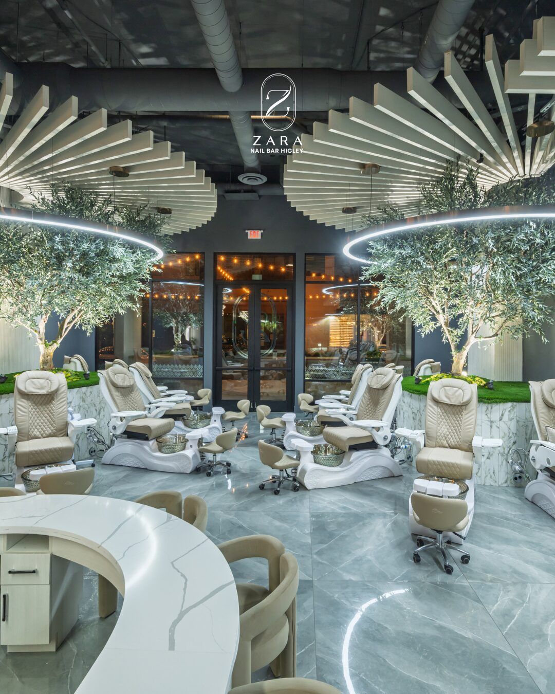 The pedicure lounge at Zara Nail Bar Higley: cream chairs beneath olive trees and a ribbed ceiling, with the Zara sign above the glass entrance.