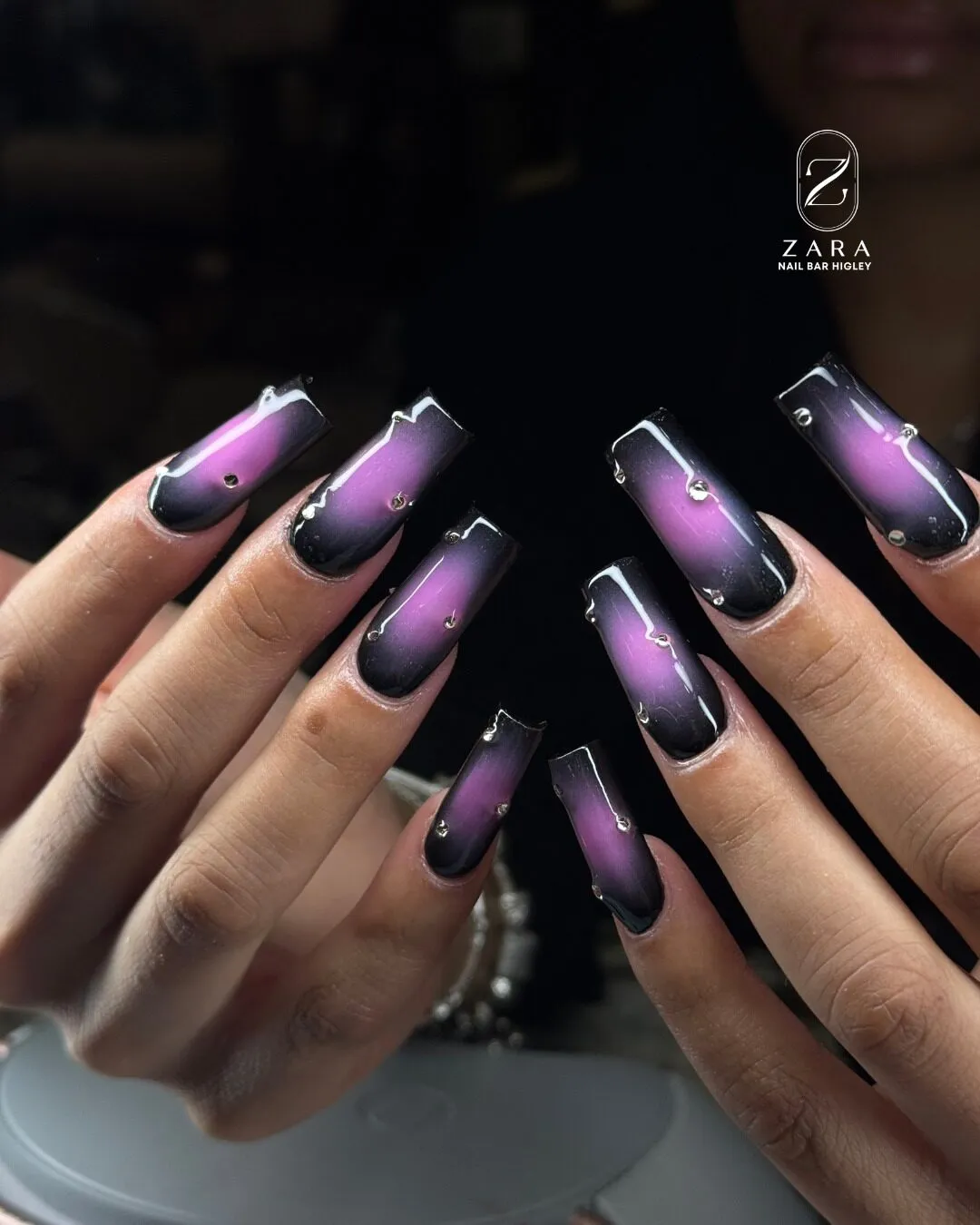 Long coffin nails with a purple aura fading into black, finished with small crystals.